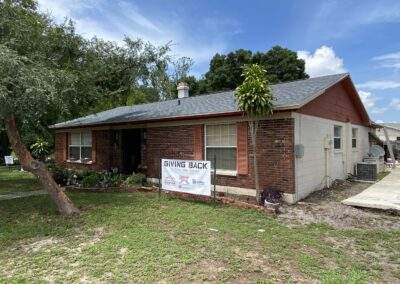 Front view of a brick home during a community roofing giveaway project