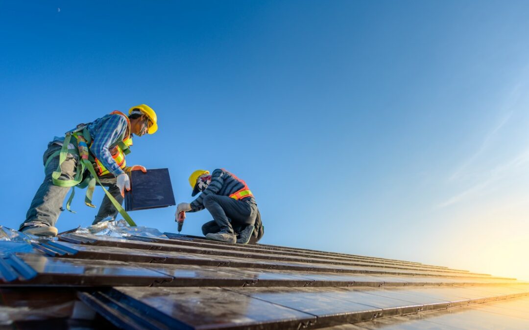 Two male workers wearing safety clothes Installing the roof tile
