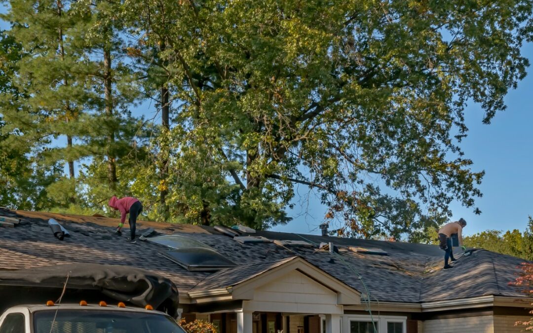 Roofers removing old material from a house in preparation for storm damage repair