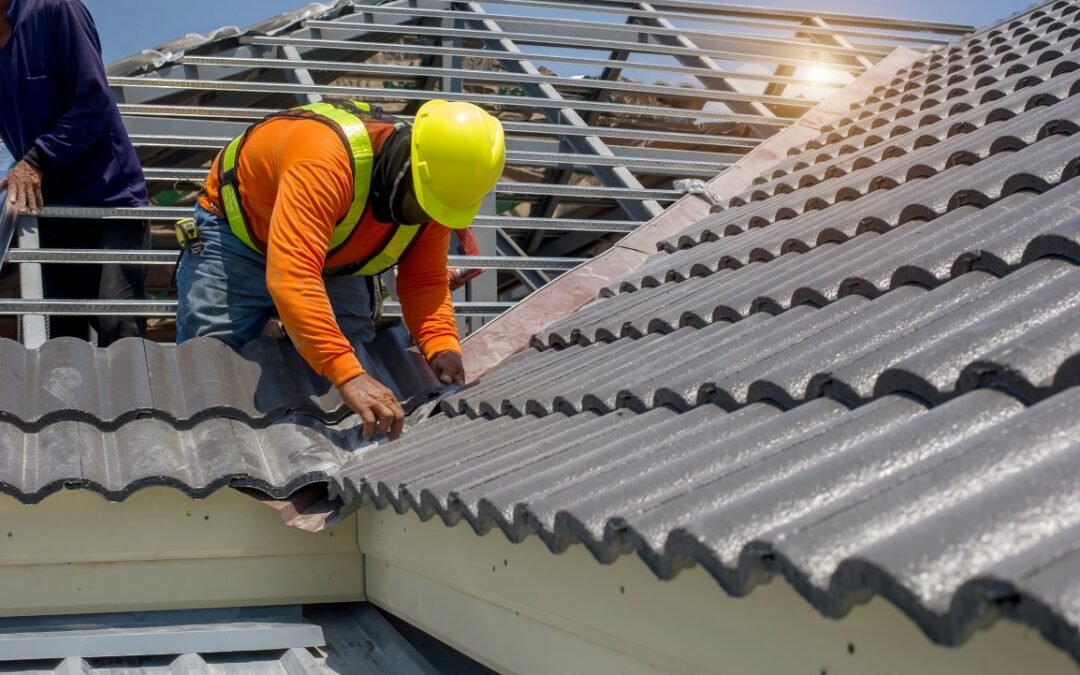 Roof repair, construction worker repairing roof,replacing gray tiles or shingles on house with blue sky as background and copy space, Roofing - construction worker standing on a roof covering it with